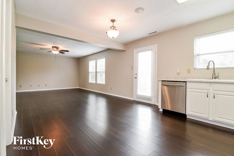 A kitchen with a stainless steel dishwasher and wooden floors.