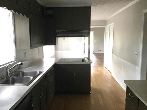 A kitchen with black cabinets and a wooden floor.