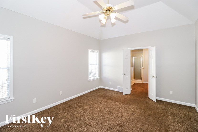 A room with a carpeted floor and a ceiling fan.