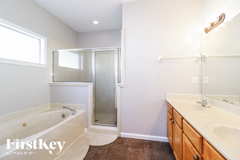 A white bathroom with a brown carpet and a tub and sink.
