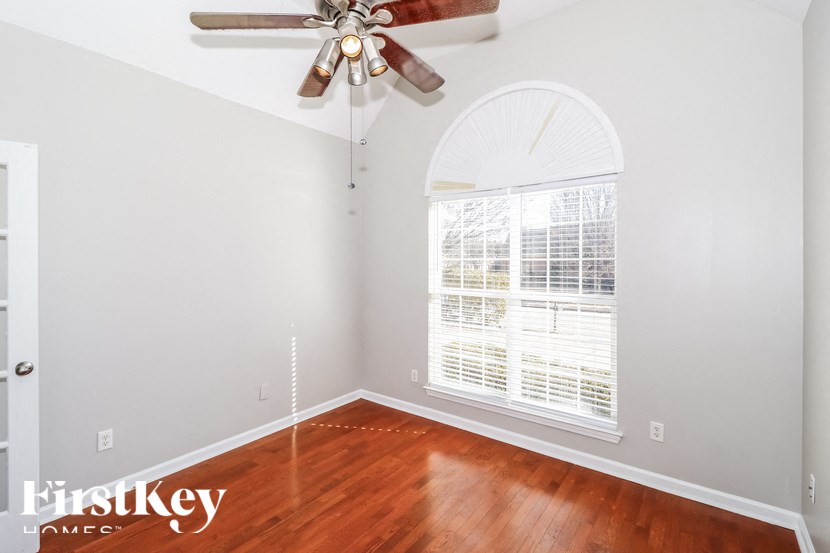 A room with a fan and a window with blinds.
