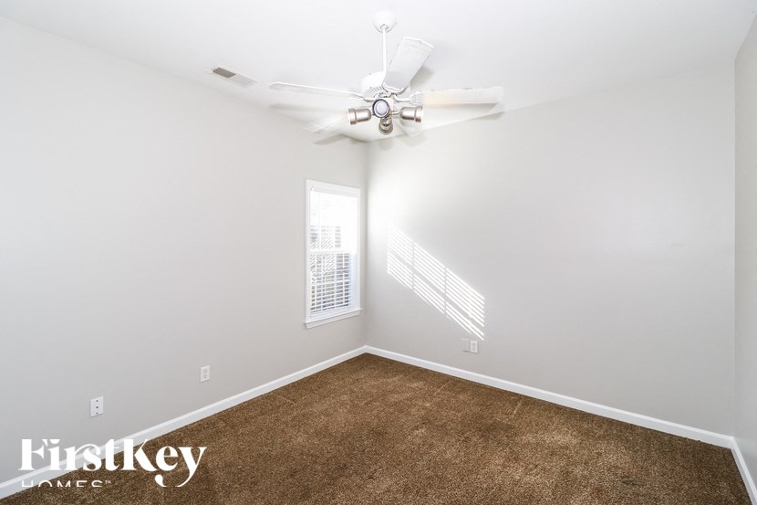 A room with a carpeted floor and a ceiling fan.