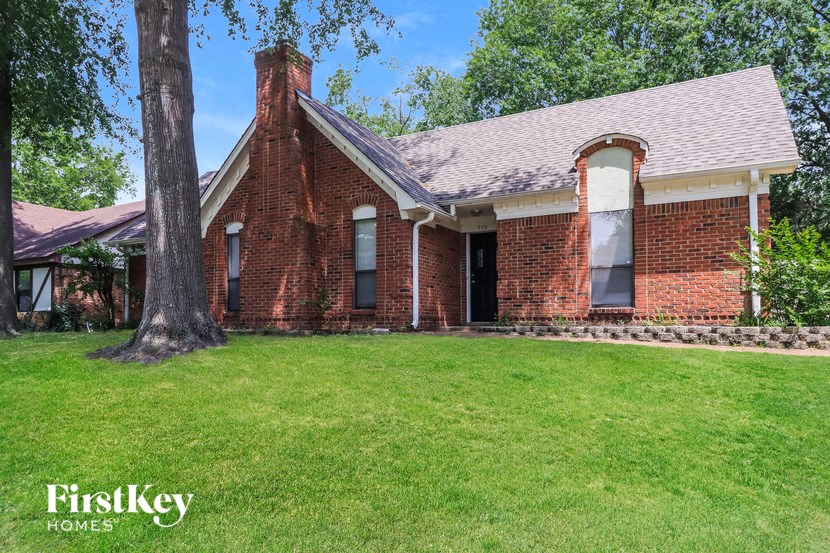 an old brick house with a grass lawn and a tree