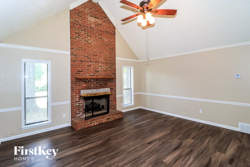 a living room with a brick fireplace and a ceiling fan