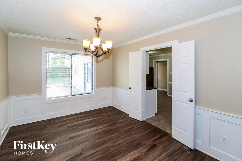 a dining room with white walls and wood flooring and a window