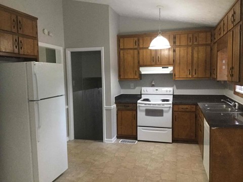 A kitchen with a white refrigerator, black countertops, and wooden cabinets.
