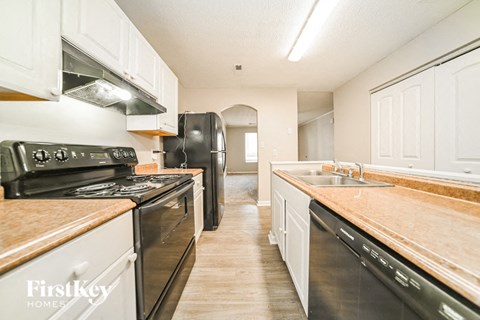 A kitchen with black appliances and wooden countertops.