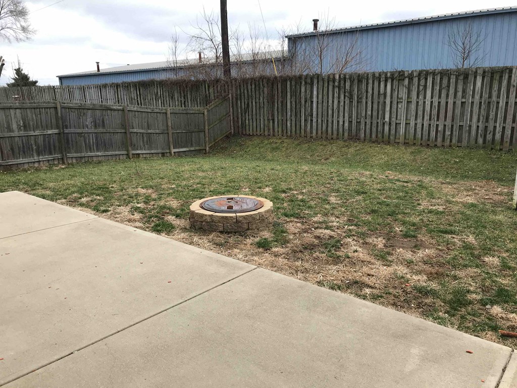 a backyard with a fire pit and a wooden fence