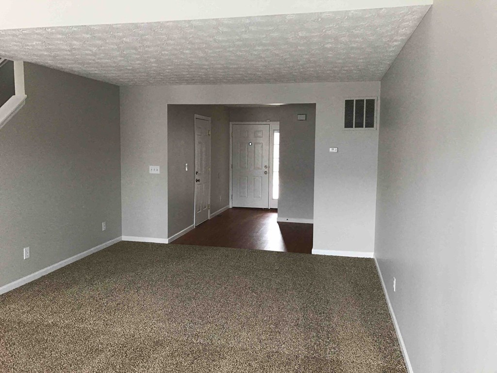 an empty living room with white walls and a carpet