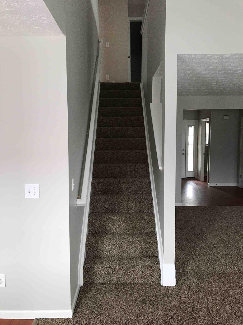 a view of the stairs from the living room up to the dining room and kitchen