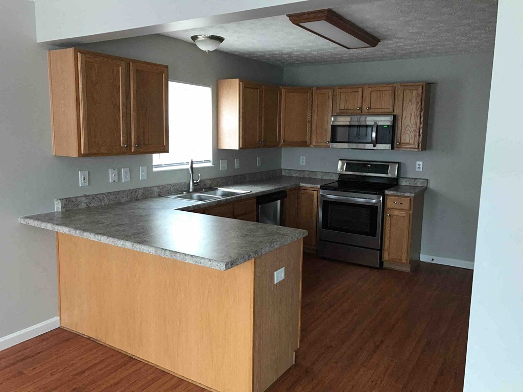 an empty kitchen with wooden cabinets and stainless steel appliances