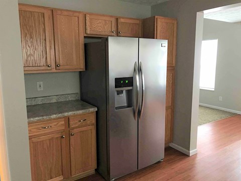 a stainless steel refrigerator in a kitchen with wooden cabinets