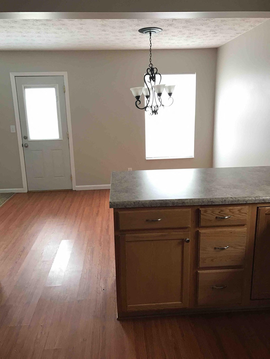 an empty kitchen with wooden floors and a chandelier