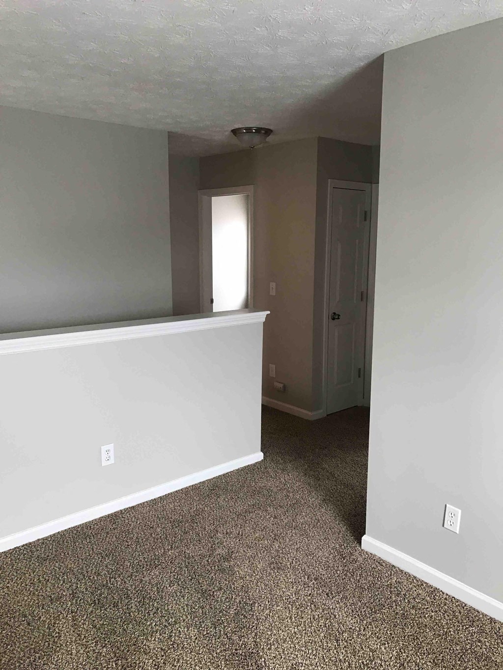 an empty living room with a white wall and carpet