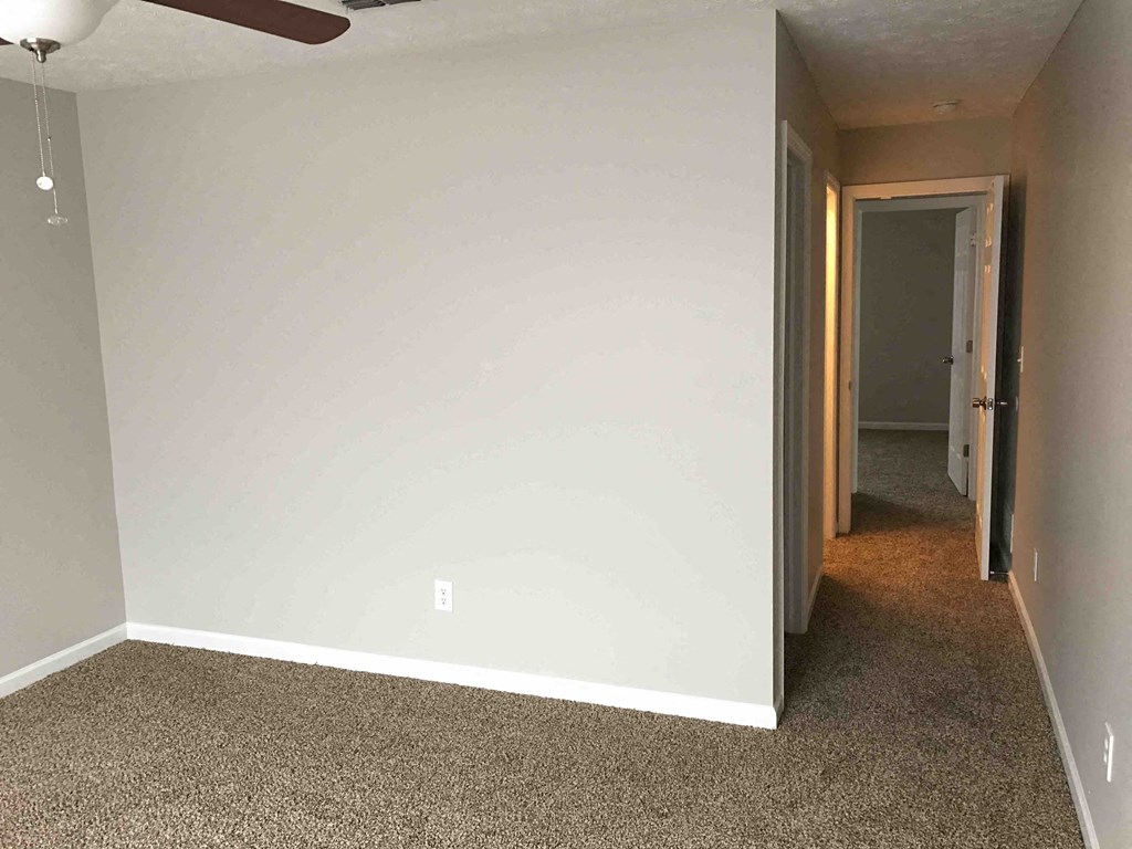 an empty living room with a white wall and carpet