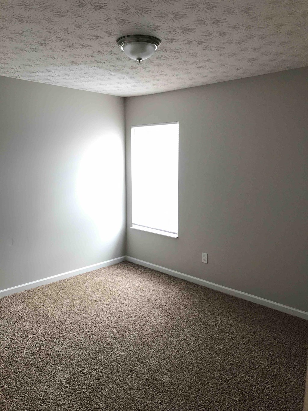 an empty room with a window and a carpet