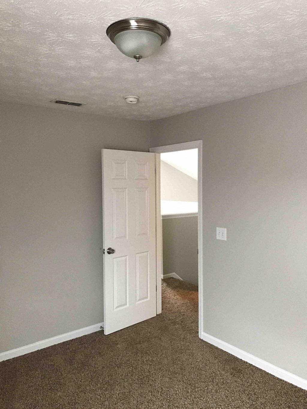 an empty room with a white door and a ceiling light