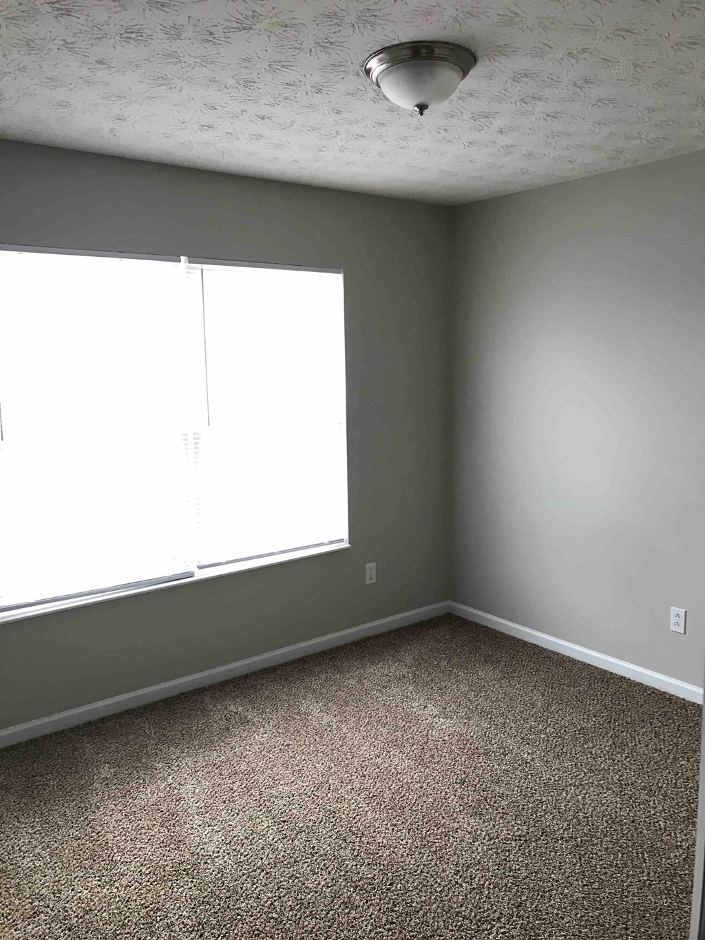 an empty room with gray walls and a window