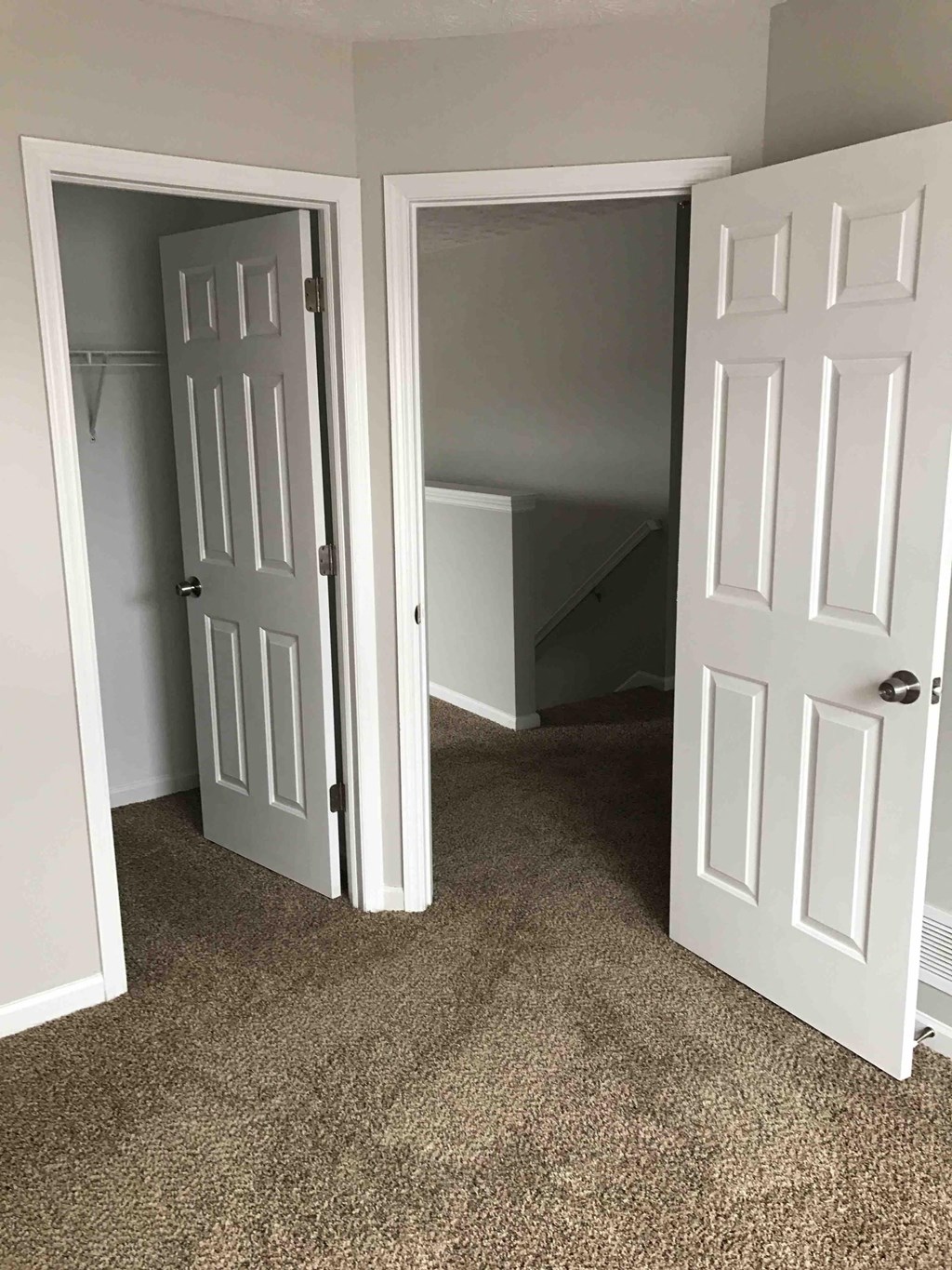 a room with two doors and a carpeted floor and a closet