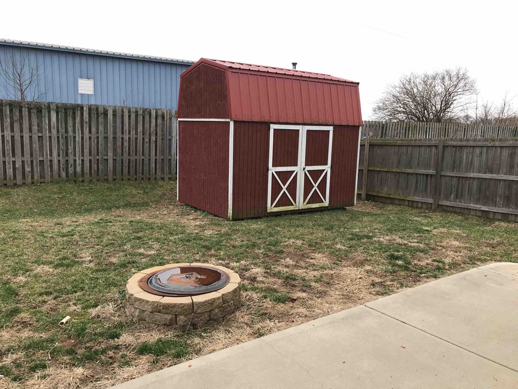 a small barn with a fire pit in the yard