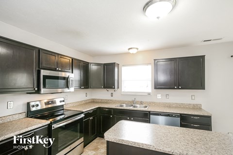 A kitchen with black cabinets and a granite countertop.