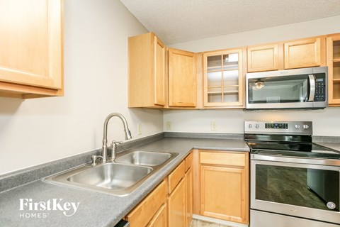 A kitchen with wooden cabinets and a stainless steel sink and oven.