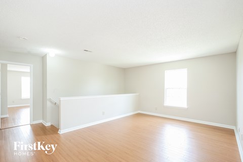 A spacious empty room with wooden floors and white walls.