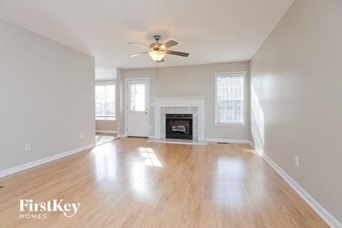 A spacious living room with a fireplace and a ceiling fan.