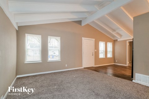 A spacious room with a carpeted floor and a door on the right side.