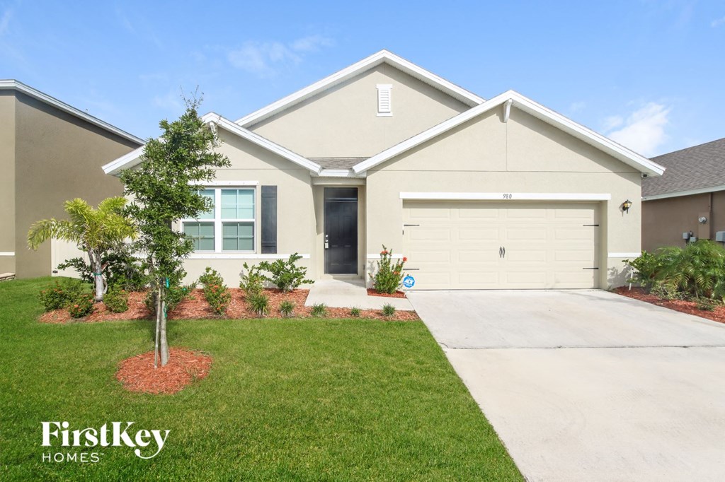a beige house with a lawn and a driveway