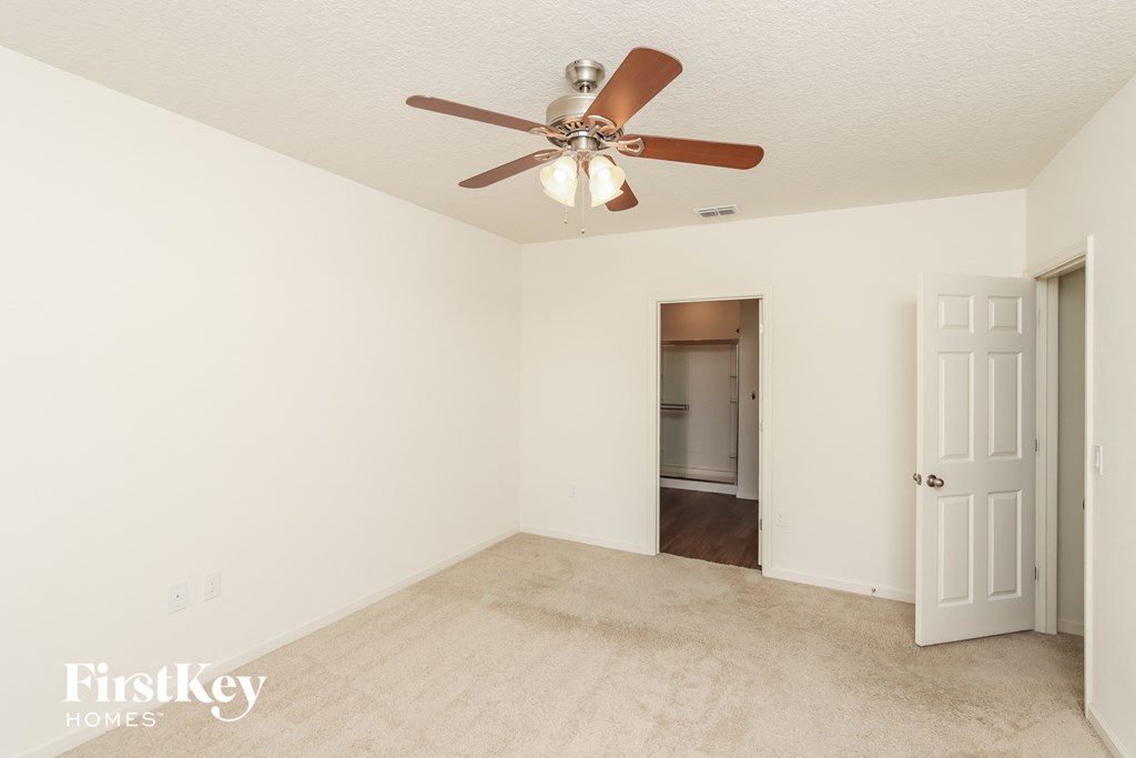 a living room with a ceiling fan and a door to a hallway