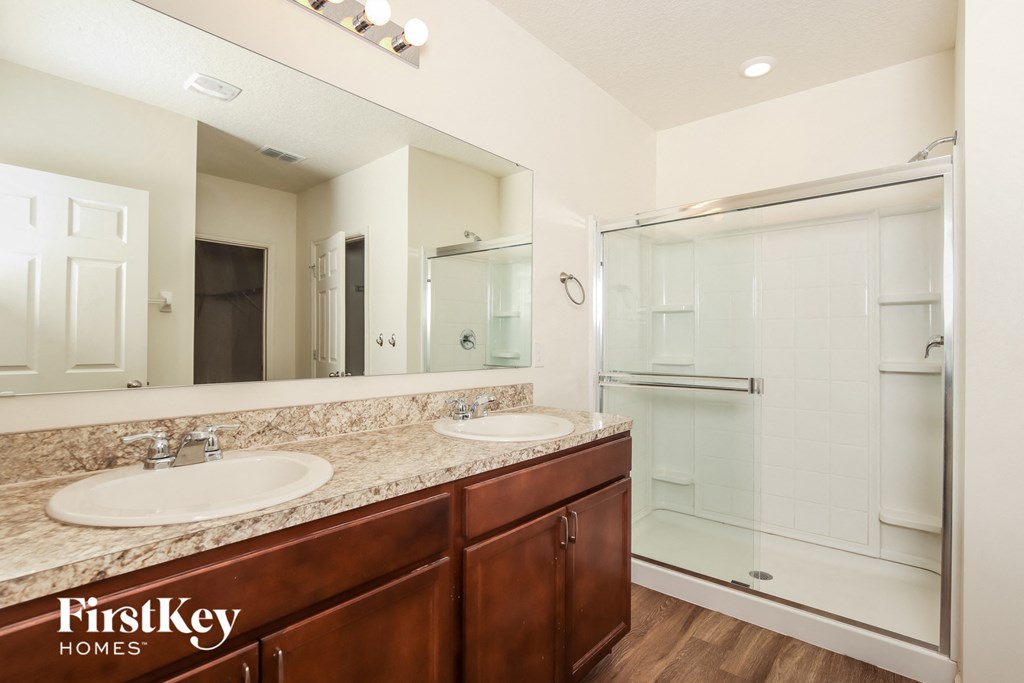 a bathroom with two sinks and a large mirror and a shower
