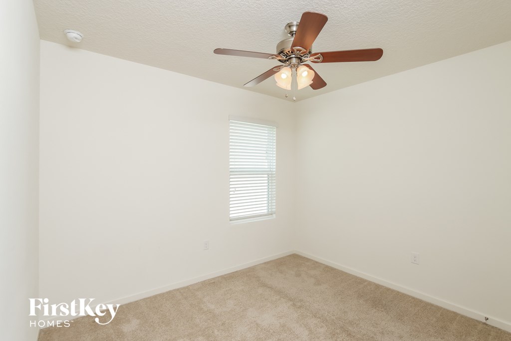 a bedroom with white walls and a ceiling fan