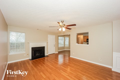 A spacious living room with a fireplace and a ceiling fan.