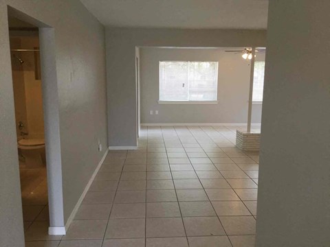 an empty living room with a tiled floor and a window