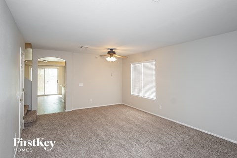 a spacious living room with carpet and a ceiling fan