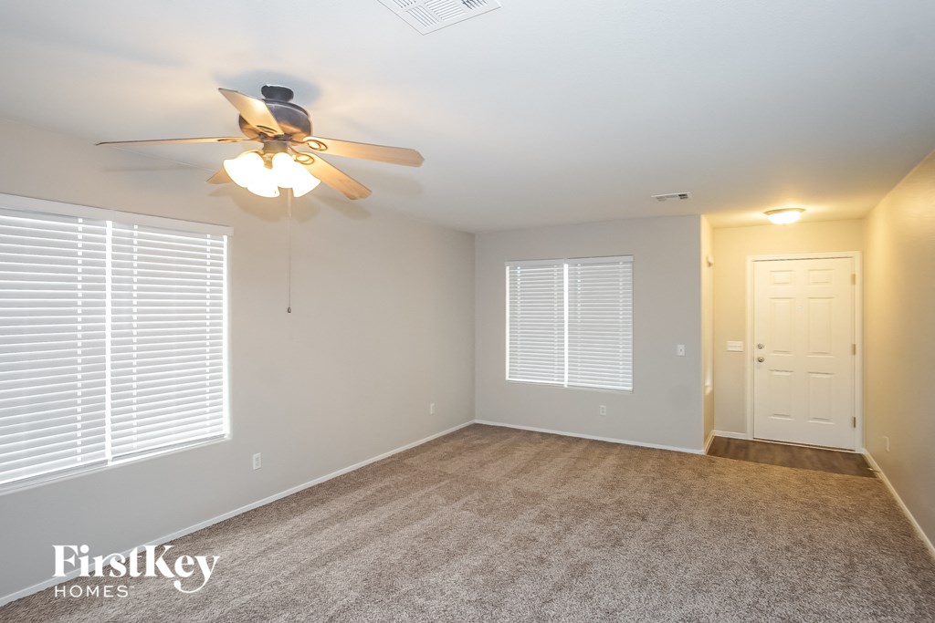 the living room of an empty house with a ceiling fan