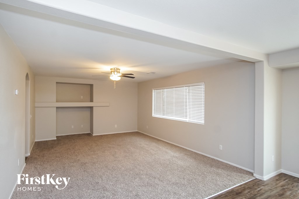 an empty living room with a ceiling fan and a window