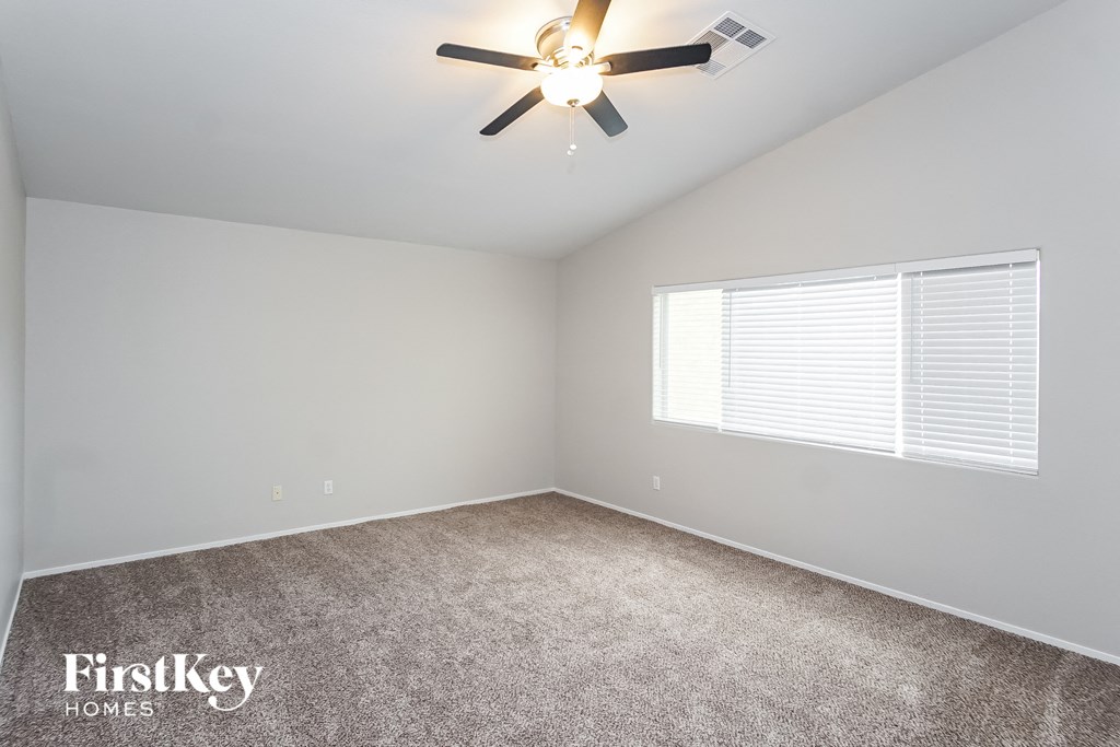 the spacious bedroom has carpeting and a ceiling fan
