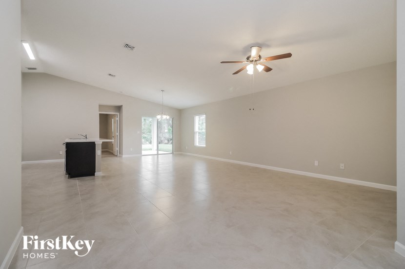 an empty living room with a ceiling fan and a large space