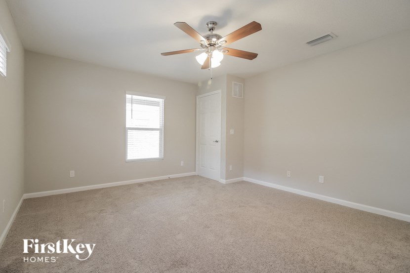 an empty living room with a ceiling fan and a door