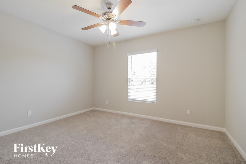 an empty room with a ceiling fan and a window