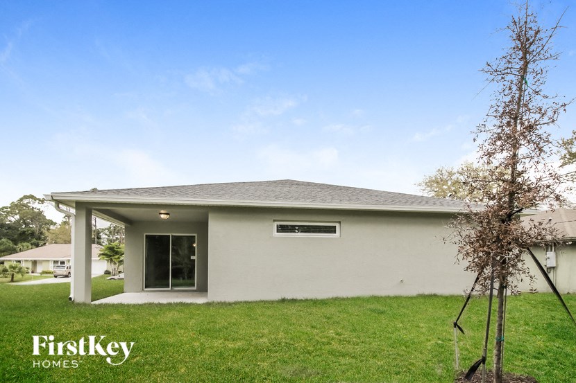 a white house with a lawn and a tree
