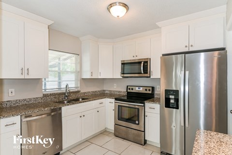 A kitchen with a stainless steel refrigerator and a stove top oven.