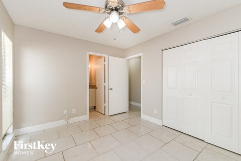 A spacious room with a ceiling fan and two doors.