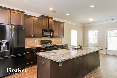 A kitchen with dark brown cabinets and a black refrigerator.