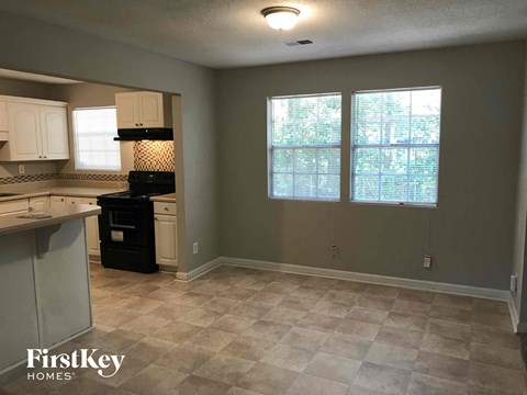 A kitchen with a black stove top oven and a tiled floor.