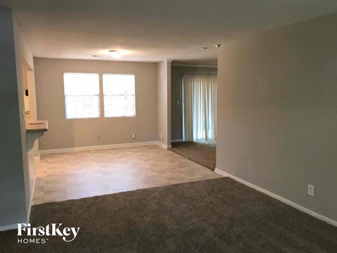 A spacious room with a carpeted floor and a door leading to another room.