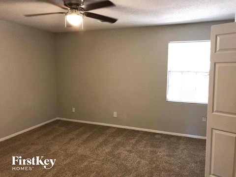 A room with a carpet floor and a ceiling fan.