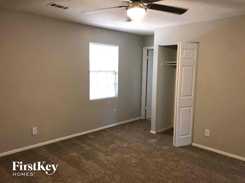 A carpeted room with a ceiling fan and a doorway leading to another room.